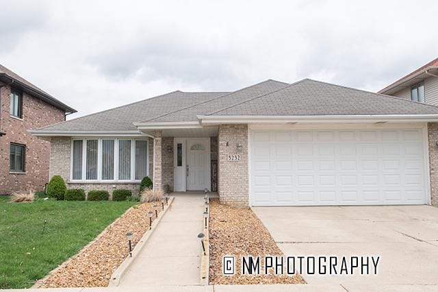 view of front of property with brick siding, driveway, a front lawn, and a garage