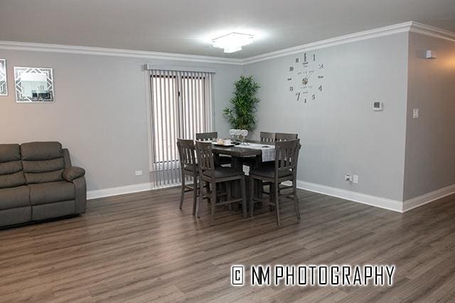 dining space featuring crown molding, wood finished floors, and baseboards