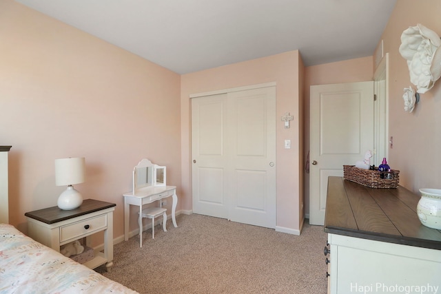 carpeted bedroom with a closet and baseboards