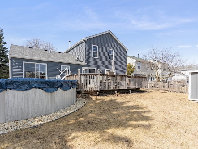 back of property with a deck, a fenced in pool, and fence