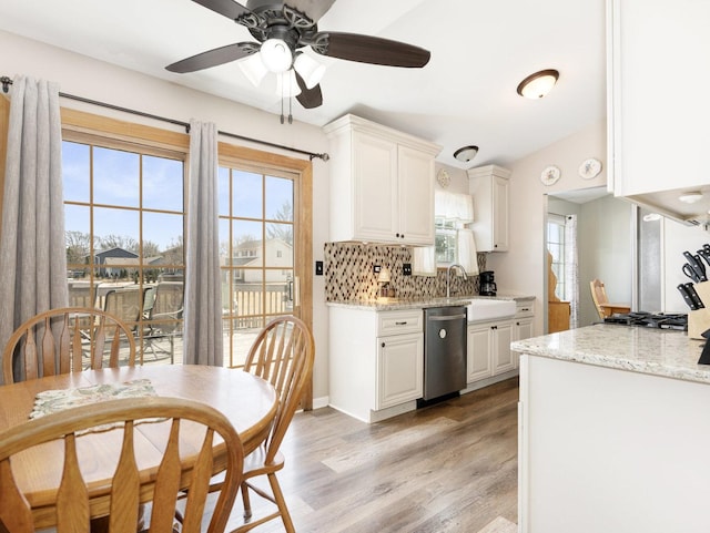 kitchen with backsplash, light wood-type flooring, stainless steel dishwasher, gas cooktop, and a sink