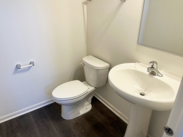 bathroom with toilet, baseboards, and wood finished floors