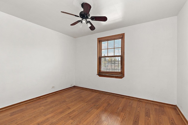 unfurnished room featuring a ceiling fan, wood finished floors, and baseboards