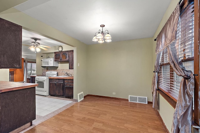 kitchen with white appliances, light wood-style flooring, dark brown cabinets, and visible vents