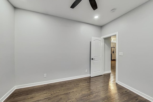 unfurnished room featuring baseboards, a ceiling fan, and dark wood-style flooring