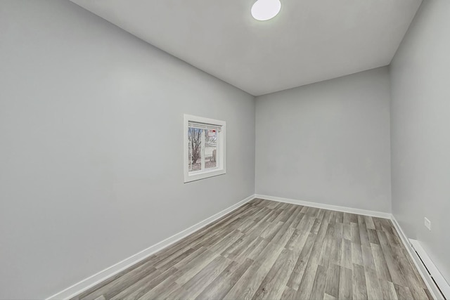 unfurnished room with baseboards, light wood finished floors, and a baseboard radiator