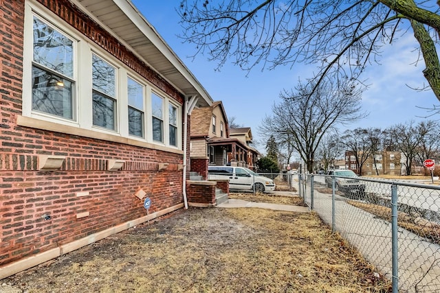 view of side of home with fence, brick siding, and a residential view