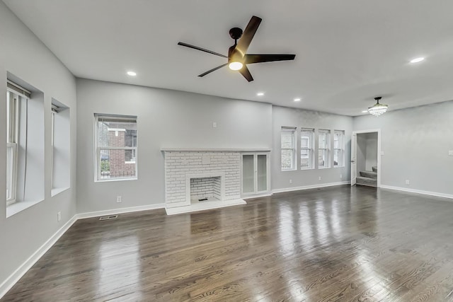 unfurnished living room featuring a ceiling fan, baseboards, recessed lighting, dark wood-style flooring, and a brick fireplace