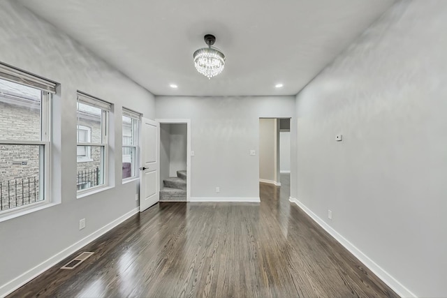 empty room featuring visible vents, a notable chandelier, stairway, baseboards, and dark wood-style flooring