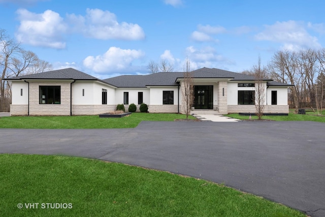 prairie-style house featuring a front lawn and stucco siding