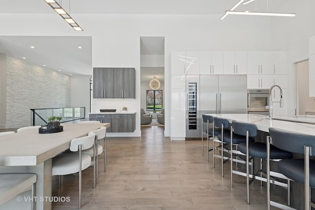 dining space featuring light wood-style floors, a towering ceiling, and recessed lighting