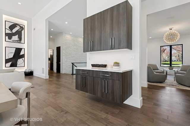 interior space with modern cabinets, open floor plan, light countertops, dark brown cabinets, and dark wood-type flooring