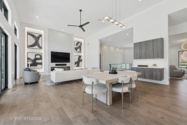 dining space with ceiling fan, recessed lighting, a high ceiling, and wood finished floors