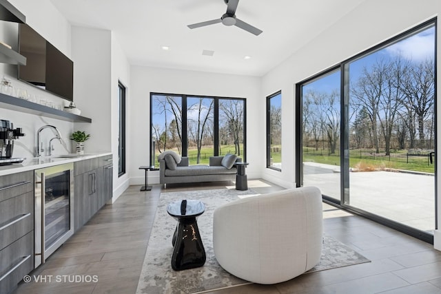 living area featuring light wood-style flooring, ceiling fan, recessed lighting, and beverage cooler