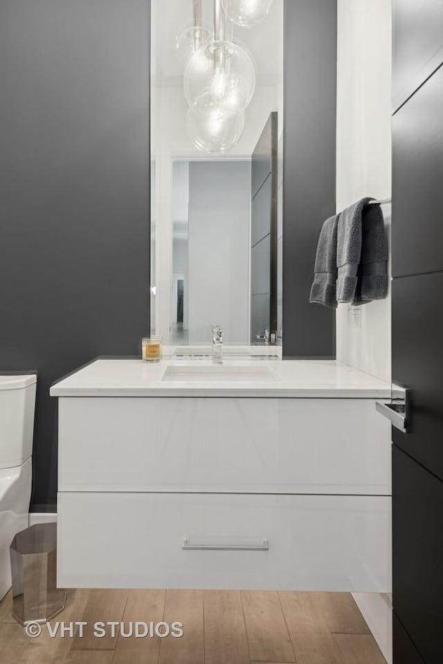 bathroom with toilet, wood finished floors, and vanity