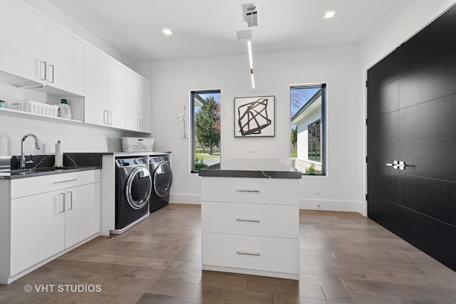 clothes washing area with dark wood-style flooring, baseboards, washing machine and clothes dryer, cabinet space, and a sink
