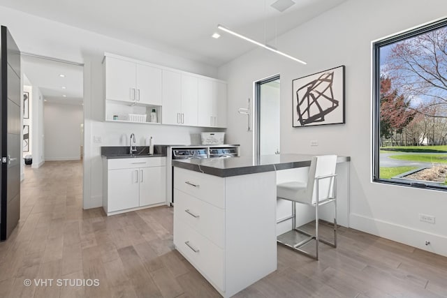 kitchen with light wood-style flooring, open shelves, and dark countertops