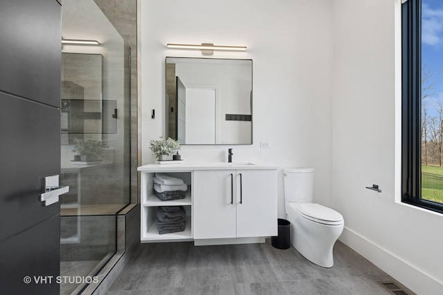 full bath featuring vanity, baseboards, toilet, tiled shower, and visible vents