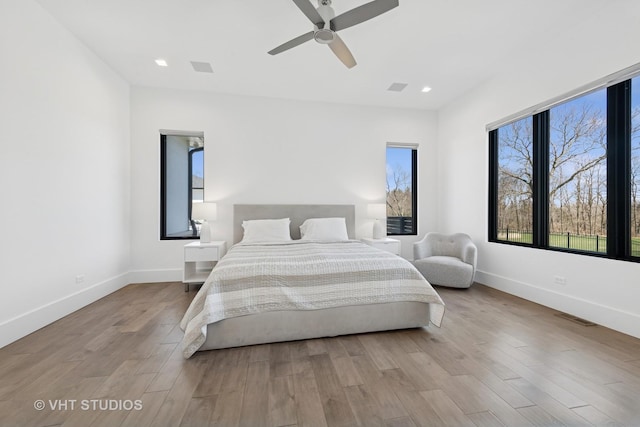 bedroom with wood finished floors, ceiling fan, baseboards, and visible vents
