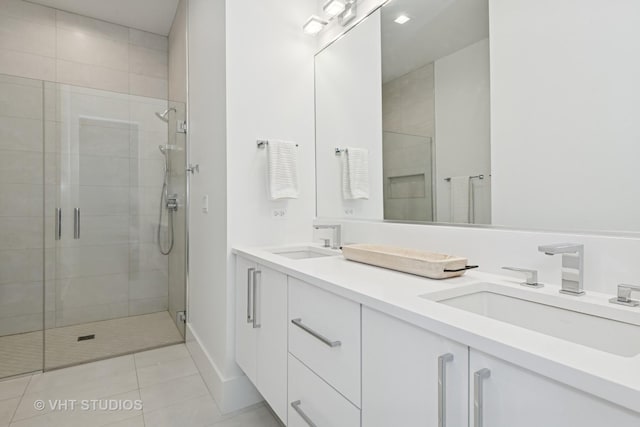 full bathroom featuring a stall shower, double vanity, a sink, and tile patterned floors
