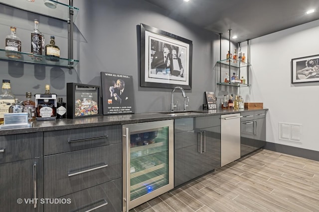 bar with wet bar, light wood-style floors, visible vents, beverage cooler, and a sink