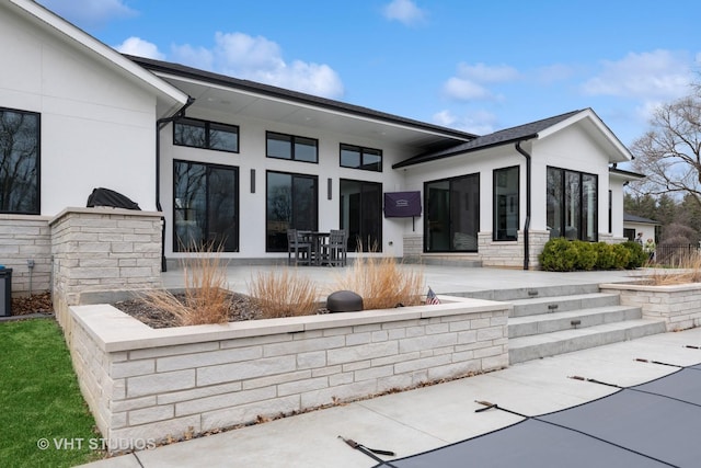 back of property with a patio area, stucco siding, and stone siding