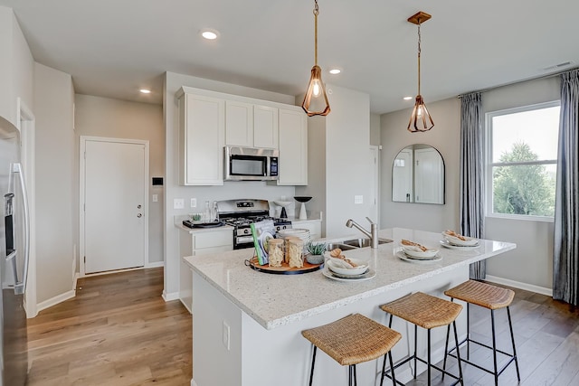 kitchen with visible vents, a sink, light wood-style floors, appliances with stainless steel finishes, and white cabinets