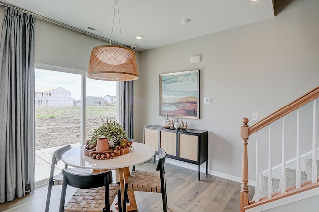 dining area featuring baseboards, light wood-style flooring, and stairs