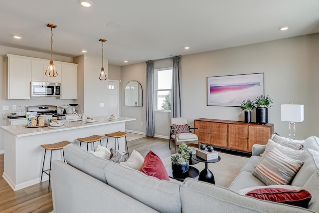 living area featuring recessed lighting, light wood-type flooring, and baseboards