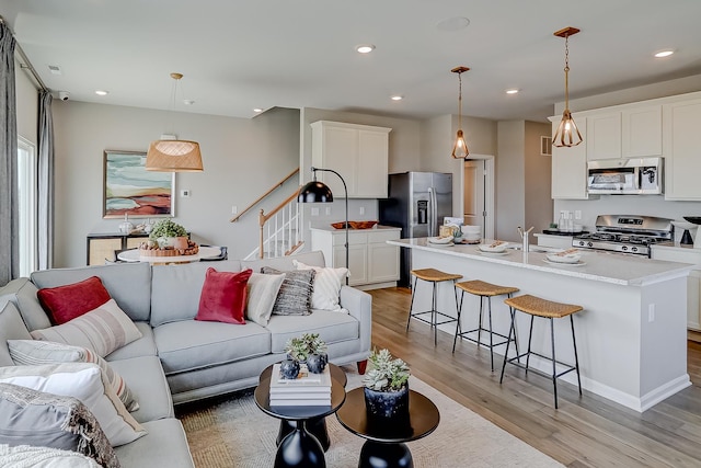 living room featuring recessed lighting, stairway, visible vents, and light wood finished floors