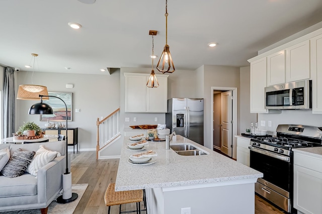 kitchen with light stone countertops, light wood-style flooring, recessed lighting, a sink, and stainless steel appliances