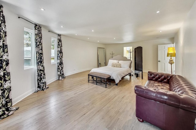 bedroom with recessed lighting, arched walkways, light wood finished floors, and baseboards