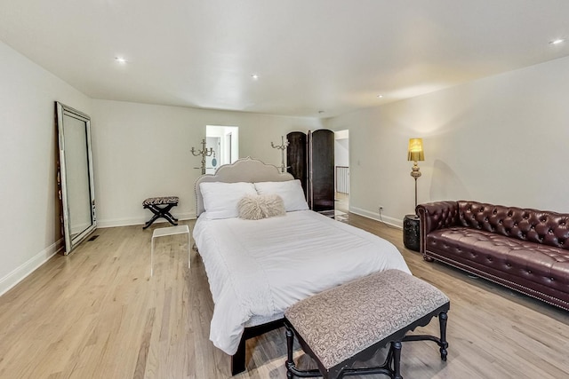 bedroom with baseboards, arched walkways, and light wood finished floors