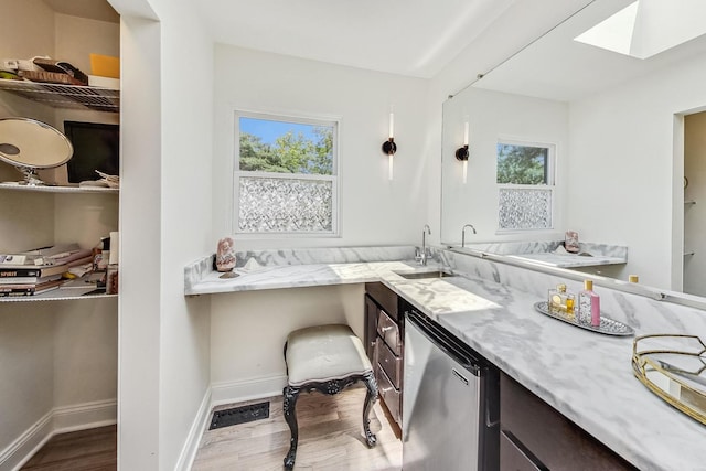 bathroom with vanity, a skylight, wood finished floors, and baseboards