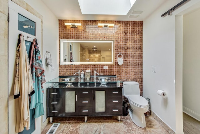 bathroom with backsplash, baseboards, toilet, and vanity