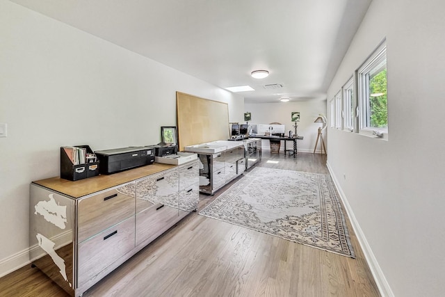 home office with light wood-style flooring, visible vents, and baseboards