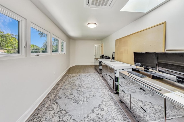 home office with light wood-style flooring, a skylight, baseboards, and visible vents