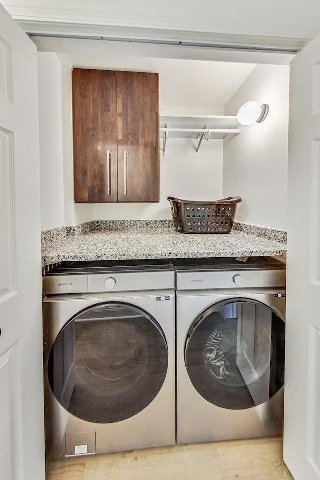 clothes washing area with cabinet space and washing machine and dryer