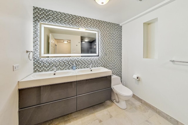 bathroom with double vanity, toilet, baseboards, and a sink