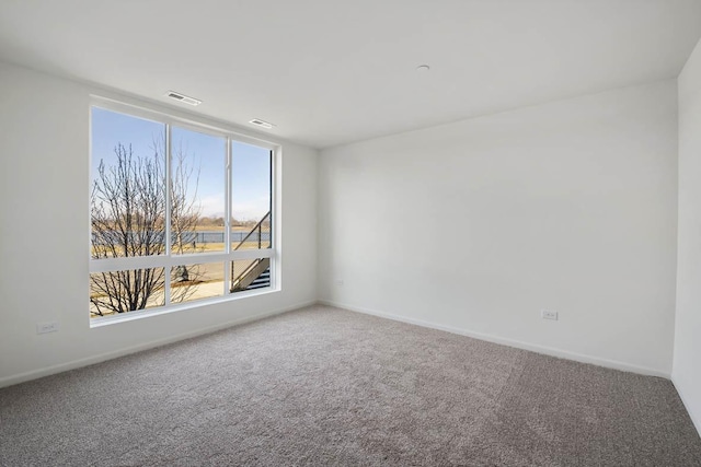 spare room featuring visible vents, carpet, and baseboards