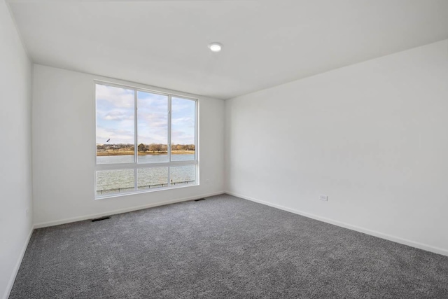 carpeted empty room with baseboards, visible vents, and a water view