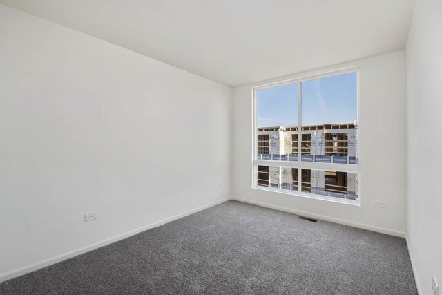 carpeted empty room featuring visible vents and baseboards