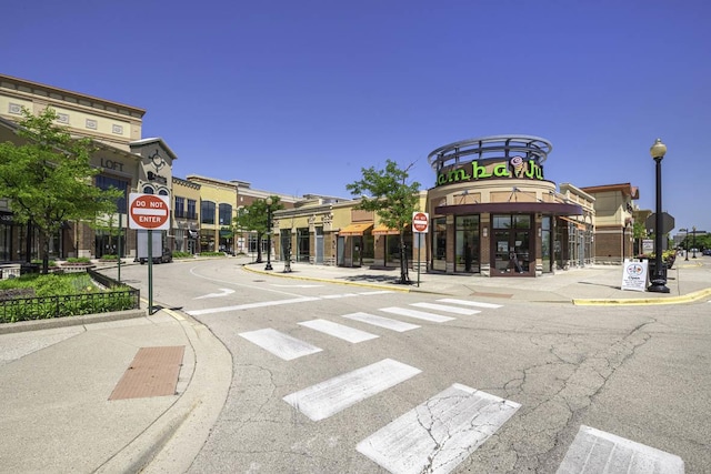 view of road featuring street lights, traffic signs, curbs, and sidewalks