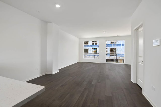 unfurnished living room featuring recessed lighting, dark wood-style floors, and baseboards