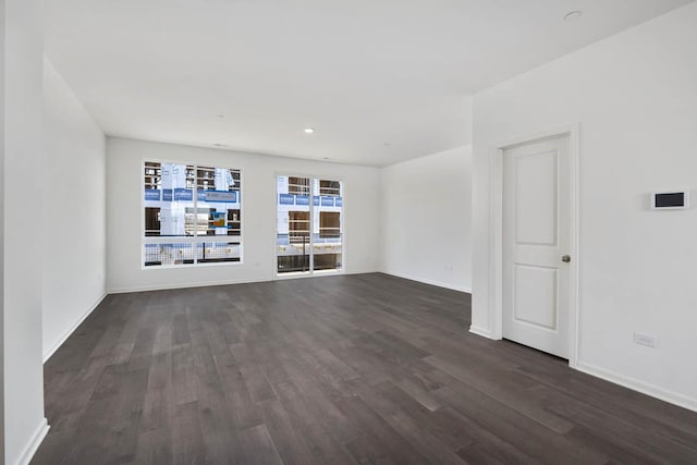 unfurnished living room with baseboards and dark wood finished floors