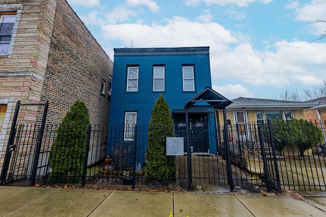 view of front of property featuring a fenced front yard, brick siding, and a gate