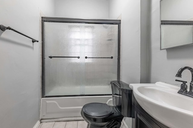 bathroom featuring tile patterned flooring, combined bath / shower with glass door, toilet, and vanity