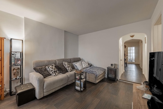 living area with arched walkways and dark wood-style flooring