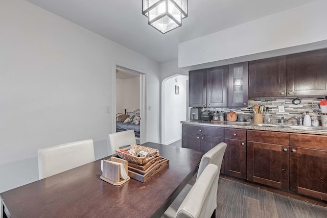 kitchen featuring tasteful backsplash, arched walkways, dark wood-style flooring, and a sink