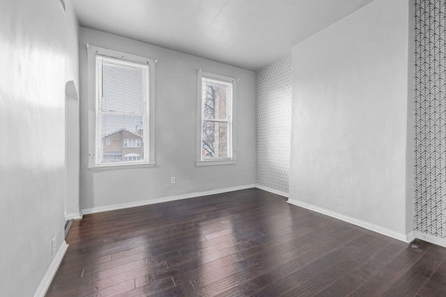 spare room featuring baseboards and wood-type flooring